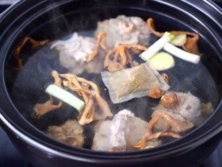 6、榛蘑山药筒骨煲,把砂锅冲洗干净后，重新放入适量的清水，放入焯过水的筒骨，加入葱段和姜片，再放入骨头汤的调料，最后把浸泡榛蘑的水和榛蘑也一起倒入砂锅里。