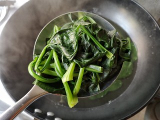 4、焦蒜皮蛋浸菠菜,将焯水后的菠菜沥水捞出。