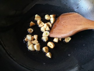 7、焦蒜皮蛋浸菠菜,用铲子翻动,让大蒜表面受热均匀。