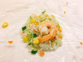 12、凤尾虾饭团,取一张保鲜膜，舀一勺饭，再放一个虾在饭的中间