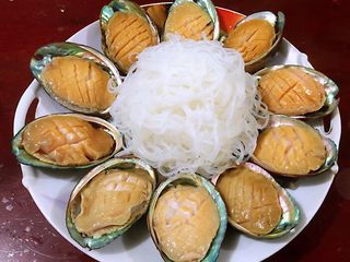 4、蒜蓉粉丝蒸鲍鱼,处理好的鲍鱼肉肉放入壳中依次摆入盘中粉丝用开水浸泡五分钟左右后沥干水分摆入盘中