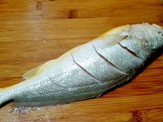 3、披红戴绿的蒜香红辣椒蒸黄鱼,冲洗干净，用刀在鱼背上面划几刀