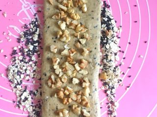 12、三麦低脂代餐健康吐司,从中间往上擀一下,往下擀一下,放上核桃颗粒,自上而下卷起,下面的边缘可以弄薄一些,便于平整。