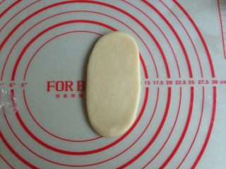 11、植物油版绿豆酥饼,将圆形的油酥皮压扁,用擀面杖擀成牛舌状