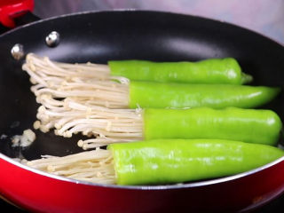 15、往青椒里塞入半斤金针菇，这味道绝了！,接着将处理好的青椒金针菇下锅煎。