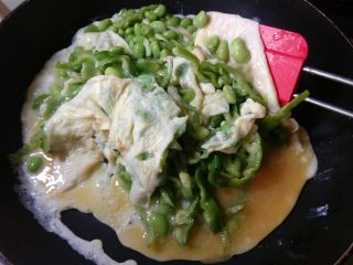 11、抱蛋青椒毛豆,锅底的蛋液凝固了，用铲子从底部铲起翻面。