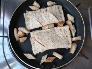 9、全麦土司香蕉派——无油低卡健身餐,平底锅预热(不用放油，不用放油，不用放油，重要的话说三遍)，将香蕉派下锅，切下来的土司边也不要浪费，可以切成小块一起下锅。