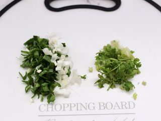 2、快手酸汤大馅馄饨,把蒜苗和香菜用刀切碎。