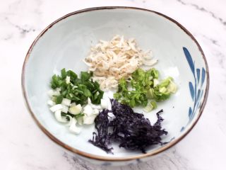 3、快手酸汤大馅馄饨,现在来做馄饨汤汁，取一个大一点的碗，放入切碎的蒜苗和香菜，虾皮和紫菜。