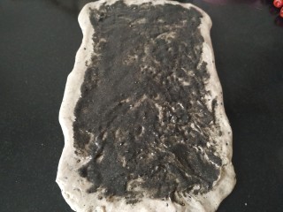 7、黑芝麻全麦核桃红枣软欧包~~安安原创,把混合了黄油，枫糖和黑芝麻粉的黑芝麻枫糖酱涂抹在擀成长方形的面团上面，四周边缘留一厘米宽的空白，做收口用；