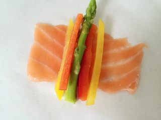 1、彩蔬鱼片卷,将三文鱼片展开，平铺，放上芦笋和彩蔬细条，然后顺势卷起来就好啦。