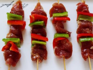 13、超爽的麻辣孜然烤肉串,把腌制好的肉和青红椒依次串到竹签上。