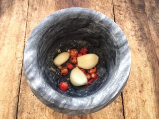 14、柠檬舂鸡脚,花生碎我还有其他舂菜用到，将舂好的花生碎舀出来，放入小米辣和大蒜。