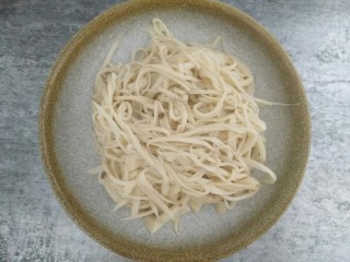 5、比肉好吃百倍的凉拌杏鲍菇,蒸熟了的杏鲍菇取出晾凉用手撕成细条,挤干水份放入碗中,一定要晾凉后再手撕,避免烫手,杏鲍菇一定要选择直直的,这样会好撕一点。