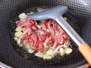 6、蒜香梅花肉炒猪血,锅烧热后倒入花生油烧热,先爆香蒜片,再放入梅花肉,大火快速翻炒均匀。