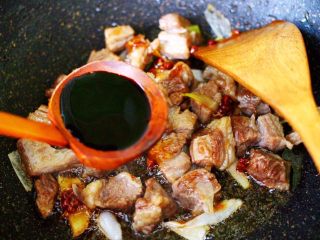 10、红烧牛肉炖大蒜,加入生抽和老抽上色调味。
