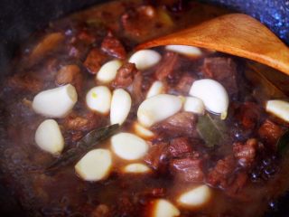 16、红烧牛肉炖大蒜,加入去皮的大蒜。