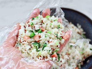 13、三色藜麦青菜饭团,取一张保鲜膜，把搅拌均匀的米饭适量放入。