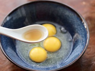 2、泡菜炒鸡蛋,把鸡蛋打入一个大一点的容器里，先加入料酒。
