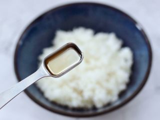 11、香椿红虾饭团,把打散的米饭放入容器中,这个时候倒入米醋来调味。