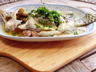 9、清蒸鳜鱼,用夹子或者戴防烫手套把鱼盘从锅里取出，放在隔热垫上。