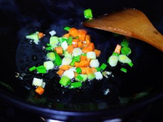 4、海虹蒜苗什锦蛋炒饭,另起锅倒入剩下的30克花生油烧热后,先爆香蒜苗和胡萝卜丁。