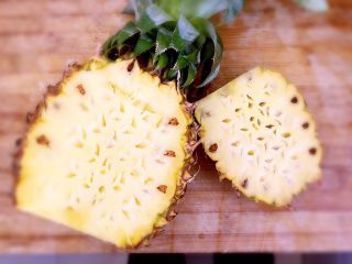 2、菠萝饭,先把菠萝洗净，底部切掉，再把菠萝直立，从三分之一处切开