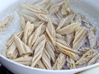 4、西芹拌腐竹,同样腐竹也用热水焯烫一下，时间不必太长，别超过一分钟，因为腐竹本身就是熟的，如果煮时间太长就会烂掉，捞出过凉水，然后挤干水分