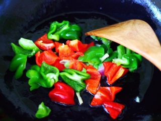 12、时蔬烩虾球,锅烧热后倒入花生油烧热后，先爆香葱姜，再放入青红椒，大火翻炒片刻。
