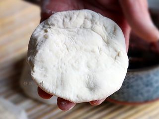 4、香甜松软的豆沙发面饼,面团松弛好以后，拿起一个剂子，用手把它按压成中间稍厚边缘薄的饼状，由于面团特别软，所以母亲做这个饼时从来不用擀面杖，这样速度也更快。