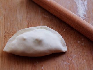 10、百吃不厌的韭菜盒子,把放入馅料的面皮用手把面皮的边边捏紧后。