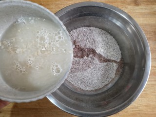 1、卡通龙猫豆沙包,将酵母粉用温水冲开，少量多次加入黑全麦粉中。