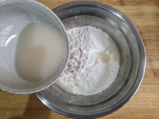 5、卡通龙猫豆沙包,将酵母粉用温水冲开，少量多次加入白面粉中。