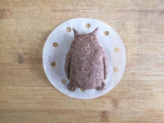 13、卡通龙猫豆沙包,按扁成椭圆形，龙猫身体造型完成，再取少量的黑麦面团做龙猫的耳朵和脚，龙猫的胳膊部分用切面板压出两道深印。