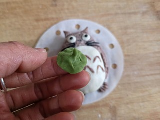 15、卡通龙猫豆沙包,用白色面团做龙猫肚皮，眼睛胡须鼻子用取少量白色面团加一点点竹炭粉来做，将龙猫表面涂薄薄一层水，将做好的配饰粘上。