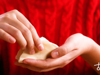 4、【清·四喜饺子】,将松弛好的面团搓成长条状,切成小份,擀面皮,填少许肉馅,将饺子皮向中间捏紧,再对角捏紧。