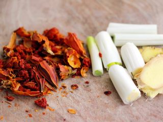 6、盐焗鸡,准备调料食材、葱洗净后切成段、姜切成薄片、栀子用工具撬碎后备用
