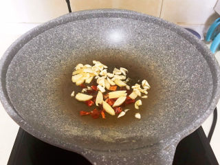 7、酱焖黄花鱼,炒锅烧热后加入大豆色拉油，油烧热后加入花椒粒和干红辣椒段，炒出香味，再加入葱姜，煸炒出香味