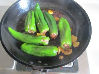 7、青椒酿肉,煸炒出香味后将酿好的青椒放入里面先干煸一下；