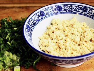3、三鲜小豆腐,烟台人的美食,好多人没吃过,简单3步教会你!,取完虾线之后,把虾仁冲洗干净后备用,把豆腐放入一个碗中,用手把豆腐全部搓碎,把摘干净的茼蒿冲洗干净后,沥干水分用刀切成碎末,把小香葱用刀切成葱花,大蒜用刀切碎备用;