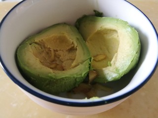 6、瘦身早餐,鸡蛋蓝莓牛油果思慕雪,用勺子挖去核,挖出果肉。