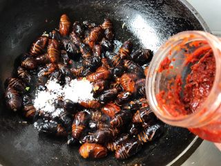 5、蒜蓉辣椒酱炒蚕蛹,放入糖和自制蒜蓉辣酱翻炒均匀