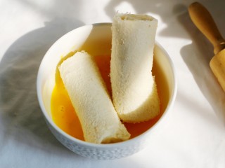 10、无敌简单的香蕉土司卷,将卷好的香蕉土司蘸上蛋液。