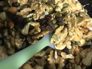 4、雪花酥,加入饼干和坚果、继续搅拌、使棉花糖均匀的沾在饼干和经过上