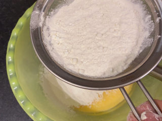 7、草莓蛋糕,将混合好的面粉和玉米淀粉过筛到蛋黄盆里，用手动打蛋器搅打均匀