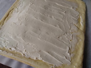 12、圣诞树根蛋糕,切去蛋糕的四条边，将打发好的淡奶油抹在蛋糕上