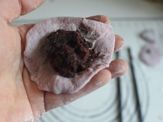 6、辅食 紫薯豆沙包（自制豆沙）,按扁之后擀成圆形，手指稍微弯曲，将豆沙包入