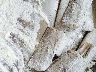 2、#年夜饭#干炸带鱼,取一个盘子、放点干面粉、把腌制好的带鱼裹一层薄薄的即可