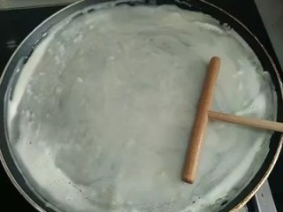 2、无油早餐鸡蛋煎饼灌饼,开中火放上平底不粘锅，锅中倒一点点油，用耙子绕着锅边拉均匀（有油刷的可以刷一遍）。等锅微微热的时候调小火，倒入调好的面（锅切不可烧得过热，要不然面糊倒入后马上会凝结不利于摊开），用耙子慢慢晕开。&nbsp;