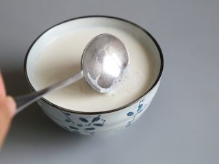 7、双皮奶,用勺子撇去泡沫后，让牛奶静至，表面产生奶皮。